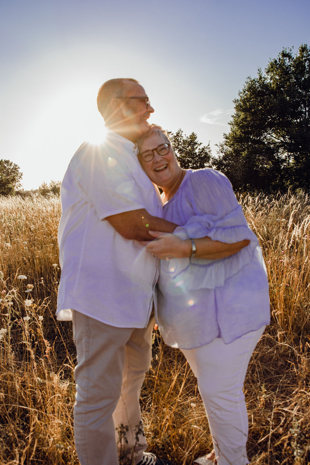 Ein älteres Paar steht im Sonnernuntergang bei einem Familienshooting in Hamm auf einem Feld. Sie sind sehr glücklich und eng aneinander.