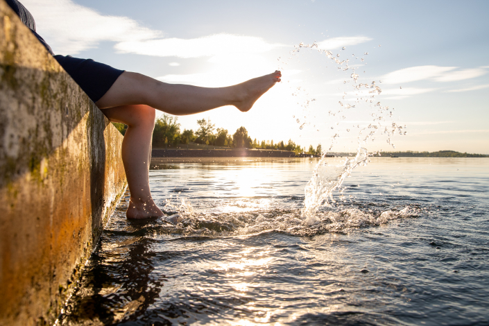 Eine Frau macht Yoga in einem See im Sonnernuntergang.
