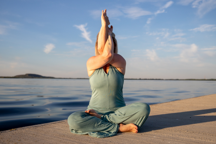 Eine Frau macht Yoga in einem See im Sonnernuntergang.