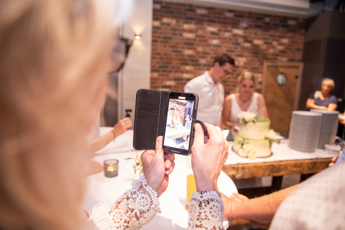 Eine Hochzeitstorte wird angeschnitten. Eine Frau fotografiert dieses mit Ihrem Handy im Maximilianpark in Hamm.