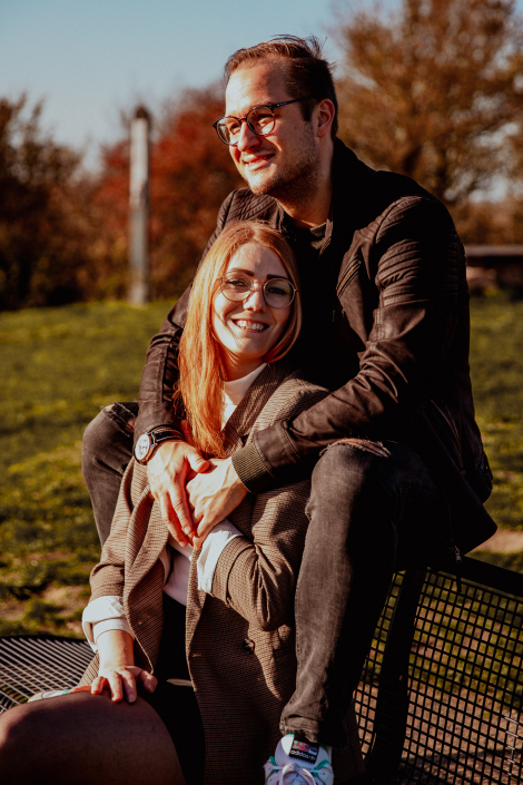 Ein glückliches Paar sitzt auf einer Bank in Hamm. Es ist Herbst und die Sonne scheint. Sie sind frisch verliebt und glücklich.